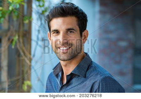 Handsome mid adult man smiling and looking at camera. Portrait of happy young casual man. Close up portrait of hispanic guy standing outdoor.