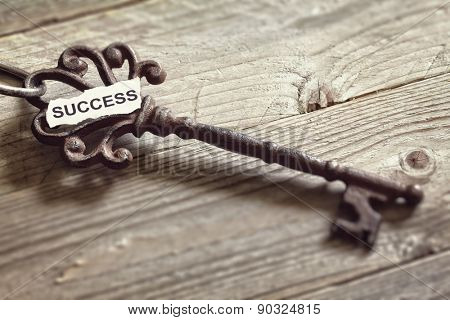 Antique key with word success written on paper resting on wooden surface concept for aspirations and success