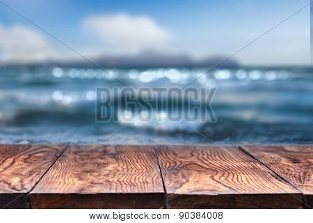 Empty wooden table with blurred sea on background, natural background with bokeh