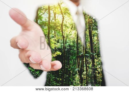 Double exposure, Businessman stretching hand to hand shake with Green trees in the forest. Eco friendly and sustainable business