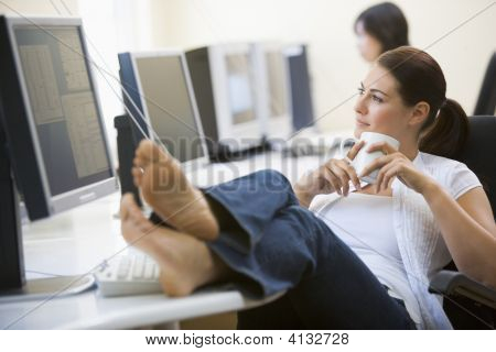 Woman In Computer Room With Feet Up Drinking Coffee