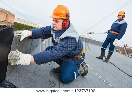 Flat roof installation. Heating and melting bitumen roofing felt 