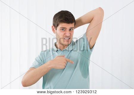 Young Man With Hyperhidrosis Pointing To A Sweat Armpit