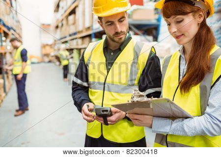 Warehouse team working together with clipboard in a large warehouse