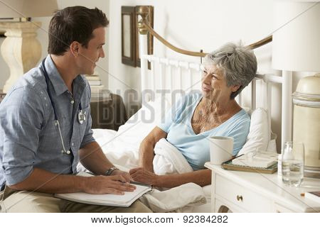 Doctor Talking With Senior Female Patient In Bed At Home