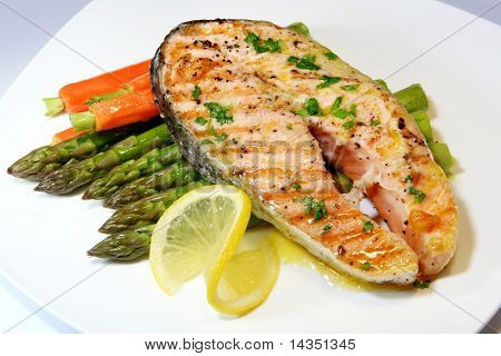 Salmon dinner, with asparagus, baby carrots, and a parsley butter sauce.  Garnished with lemon.