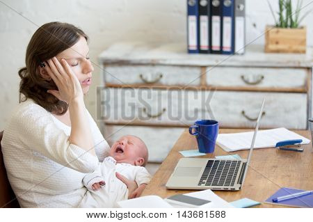 Portrait Of Young Business Mom Having Headache Because Of Crying Babe