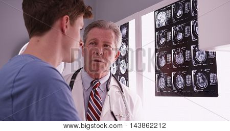 Young Male Adult Caucasian Reviewing Brain Xrays With Mid Aged Physician