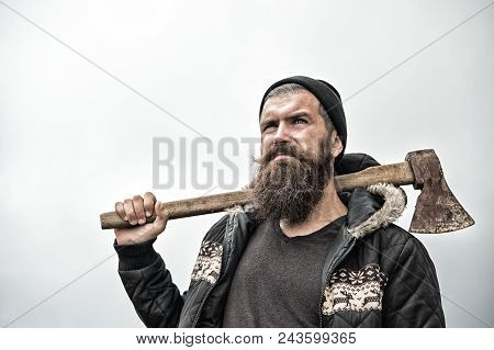 Hipster With Beard On Serious Face Carries Axe On Shoulder Sky On Background, Copy Space. Lumberjack