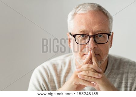 old age, problem and people concept - close up of senior man in glasses thinking