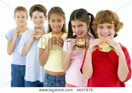 Row Of Five Young Friends Eating Hamburgers