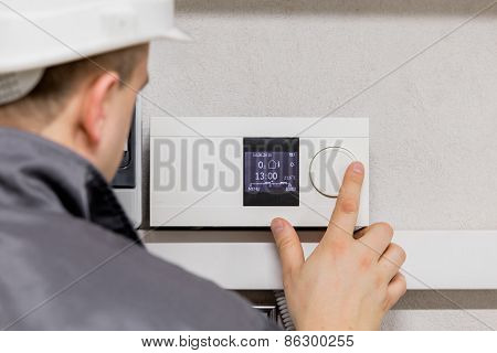 Engineer adjusting thermostat for efficient automated heating system