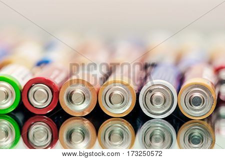 Closeup of pile of used alkaline batteries. Close up colorful rows of selection of AA batteries energy abstract background of colorful batteries. Alkaline battery aa size. Several batteries are next to each other. Many aa batteries.