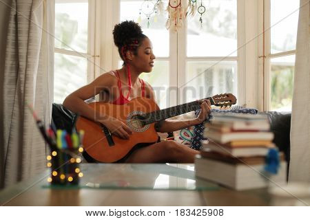 Mixed Race Girl Singing And Playing Classic Guitar At Home