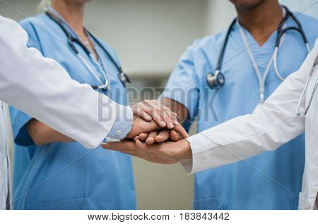 Mature doctors and young nurses stacking hands together at hospital. Close up hands of medical team stacking hands. Group of successful medical doctors and nurses stack of hands.