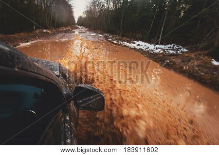 Suv 4wd car rides through muddy puddle, off-road track road, with a big splash, during a jeeping competition