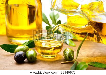 Olive Oil. Pouring Virgin Olive Oil in a bowl close up. Olives and Healthy Olive oil being poured from glass bottle. Diet. Bottle of olive oil. Dieting concept. Healthy food