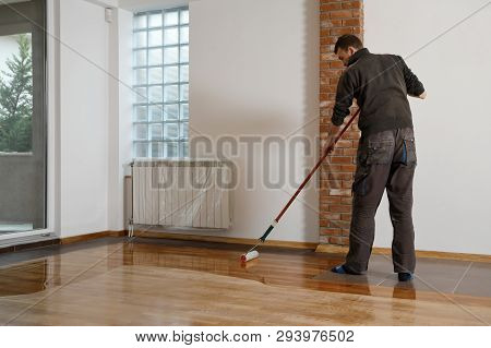 Lacquering Wood Floors. Worker Uses A Roller To Coating Floors. Varnishing Lacquering Parquet Floor 