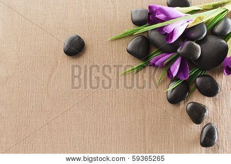 spa, heath and beauty concept - massage stones with flowers on mat