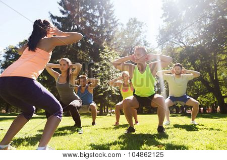 fitness, sport, friendship and healthy lifestyle concept - group of teenage friends or sportsmen exercising and doing squats at boot camp