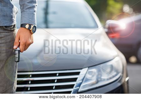 Buying used car. Car Dealer Inventory. Used cars store. Male wants to buy the car. Close-up of hand with a wrist watch, holding key from auto, finance for car concept. Happy life. Blurred background.