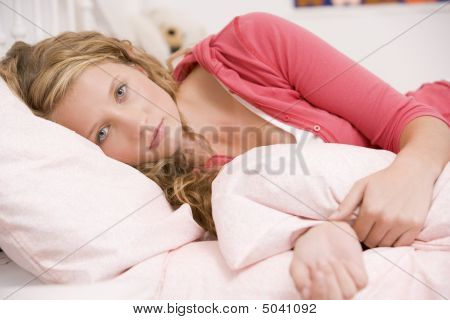 Teenage Girl Lying On Her Bed Looking Sick