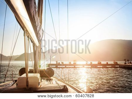 Sailboat on sunset, luxurious water transport, bright sun light on the sea, evening travel on sail yacht, summer vacation, yachting sport concept