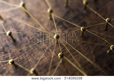 Linking entities. Network, networking, social media, internet communication abstract. Many small network connected to a larger network. Web of gold wires on rustic wood. . Shallow Depth of field.