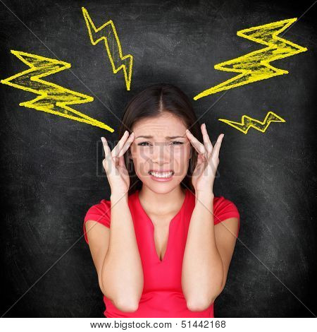 Headache - migraine and stress concept with woman in pain massaging temples for headache cure. Multi-ethnic Caucasian / Asian woman on blackboard background.