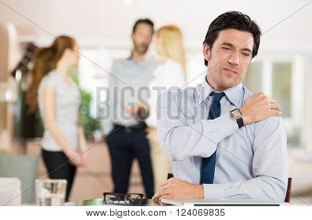 Portrait of a businessman at work suffering from shoulder pain. Portrait of stressed man holding shoulder and stretching after work. Mature business man tired and stressed after working for long.
