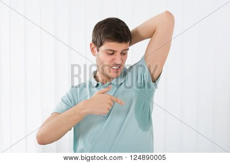 Young Man With Hyperhidrosis Pointing To A Sweat Armpit