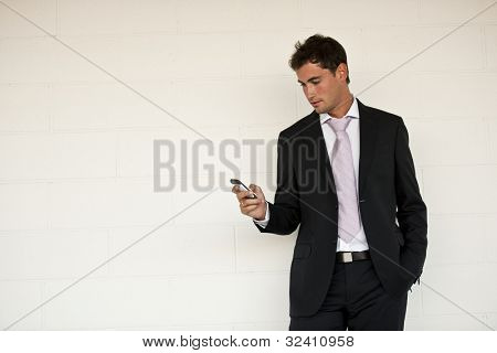 Uomo d'affari guardando il suo cellulare, forse l'invio di SMS