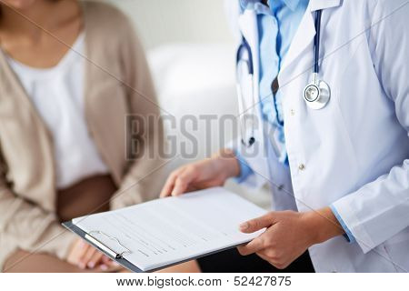 Female doctor holding application form while consulting patient