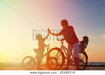 father with kids biking at sunset