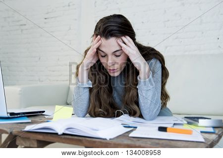 young attractive and desperate woman suffering stress doing domestic accounting paperwork bills and invoices worried and stressed at home sofa couch with laptop laptop and bank folders