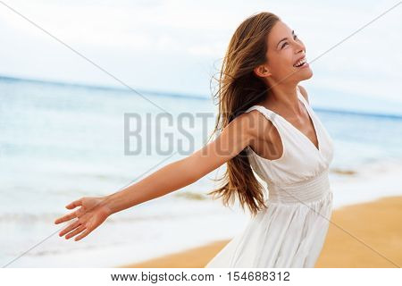 Free happy woman on beach enjoying nature. Natural beauty girl outdoor in freedom enjoyment concept. Mixed race Caucasian Asian girl posing on travel vacation holidays in dress.