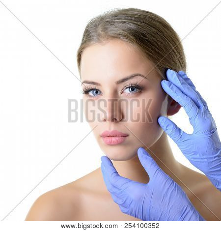 Beauty treatment for young beautiful female face, doctor's hand in gloves touch face of beautiful young woman . Skin care, beautician treatments, body wax, mink eyelashe, eyebrow grooming