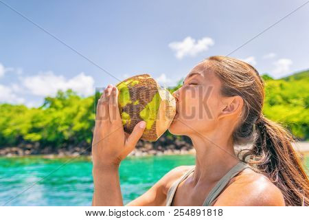 Coconut water Caribbean tropical food tourist woman drinking fresh natural from the coco on cruise ship travel vacation. Asian girl enjoying summer holidays.