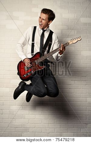 Expressive young man playing rock-n-roll music on his electric guitar. Retro, vintage style. 