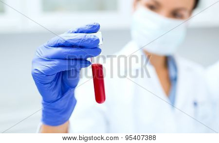 science, chemistry, biology, medicine and people concept - close up of young female scientist holding test tube with blood sample making research in clinical laboratory