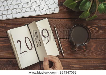 New Year 2019 Is Coming Concept. Female Hand Flips Notepad Sheet On Wooden Table. 2018 Is Turning, 2