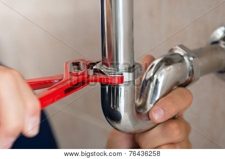 Closeup Of Plumber Fixing Pipe With Wrench