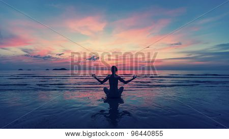 Woman doing meditation near the ocean beach. Yoga silhouette. 