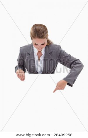 Bank employee pointing down at blank sign in her hands against a white background