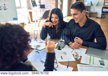 Young beautiful couple applying for mortgage. Sitting smiling happy meeting with real state agent considering mortgage loan at bank