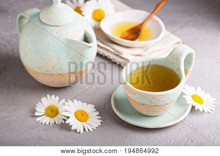 Hot camomille tea with honey in handmade ceramic cup