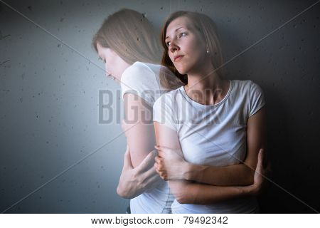 Young woman suffering from a severe depression/anxiety (color toned image; double exposure technique is used to convey the mood of unease, progression of the anxiety/depression)