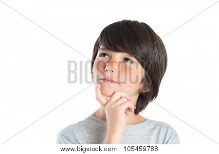 Portrait of cute boy thinking isolated on white background. Closeup shot of boy thinking with hand on chin. Male child with freckles looking up and contemplates isolated on white background.
