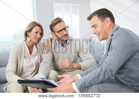 Couple with realtor signing mortgage contract