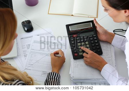 Two Female Accountants Counting On Calculator